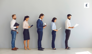 Line of job candidates standing in a row holding CVs against a grey wall